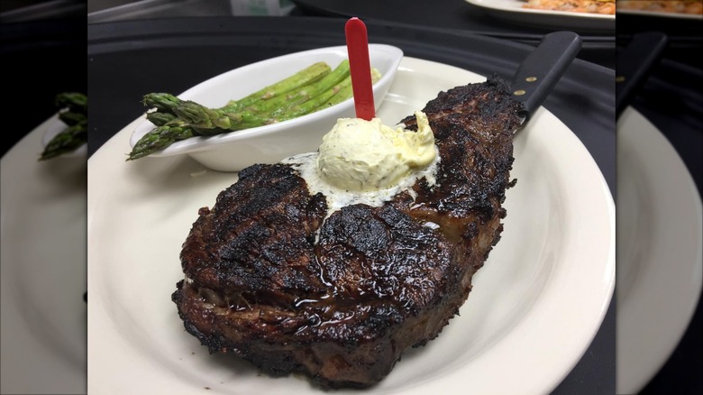 Steak topped with butter on a plate and asparagus side