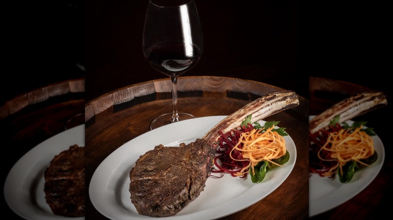 Tomahawk steak and glass of red wine on wooden tray