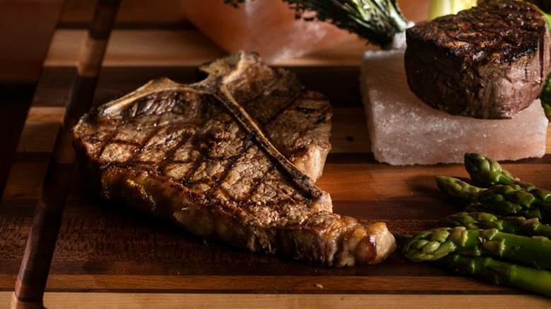 Steaks on wooden cutting board and Himalayan salt block with asparagus