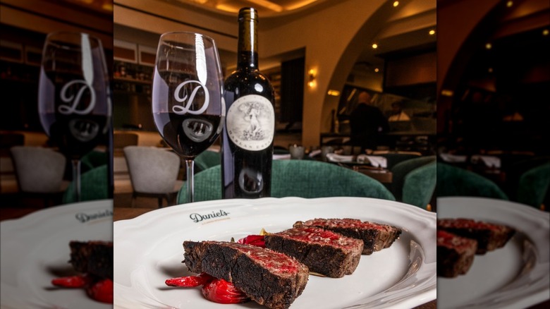 Wagyu steak sliced on a plate with bottle and glass of red wine