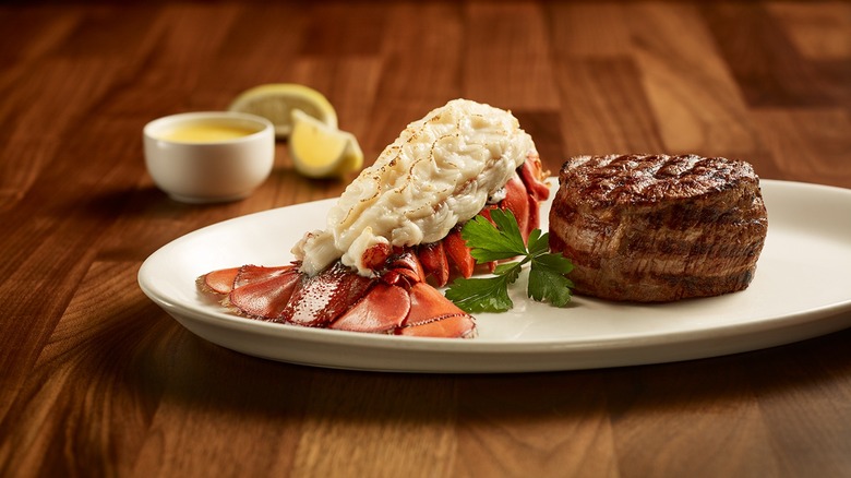 Filet and lobster tail on plate with lemon and butter in background