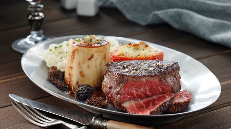 Sliced filet on plate with utensil on wood table