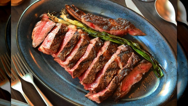 Sliced steak on blue plate with forks