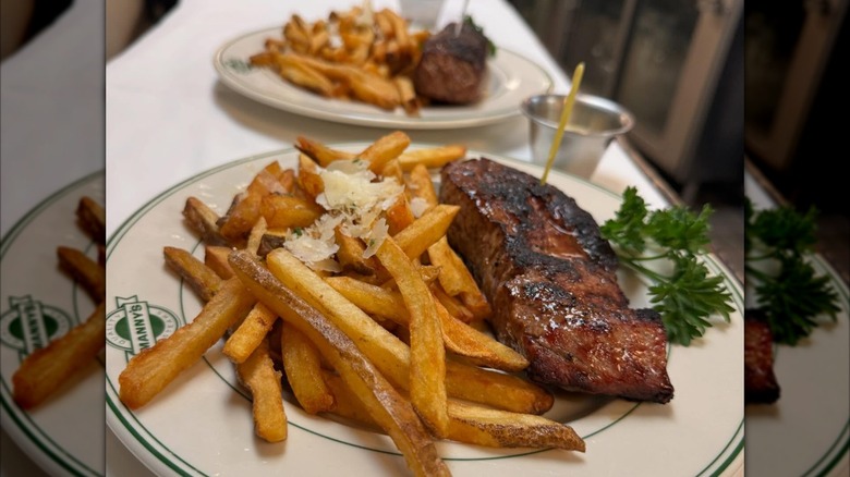 Steak and fries on plate with another blurred in background