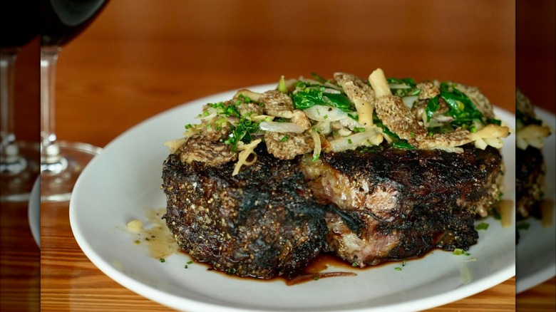 Steak with sauteed mushrooms and ramps on plate