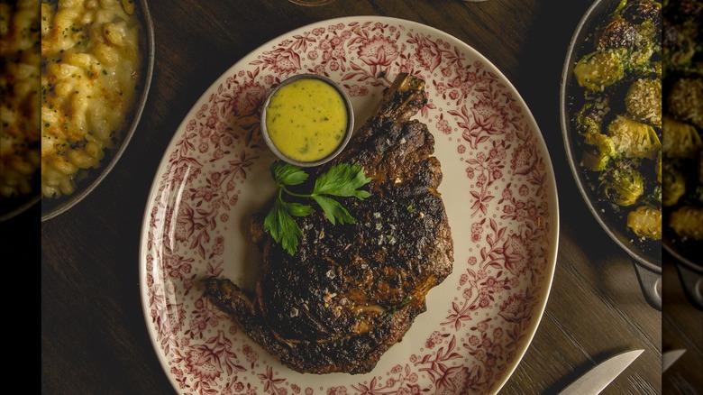Steak on plate with separate sides of mac and cheese and Brussels sprouts