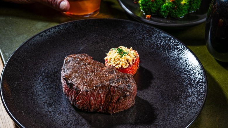 Steak on black plate with separate side of broccoli