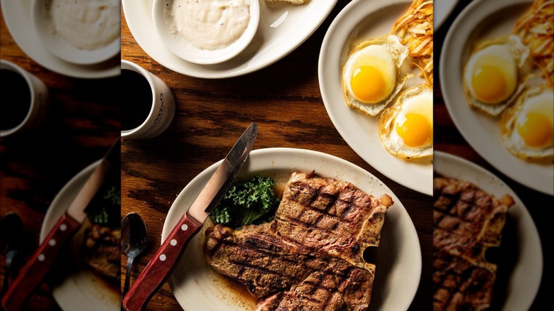 Steak with separate plates of eggs and gravy for breakfast