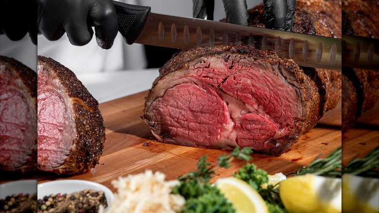Prime rib being sliced on wooden board