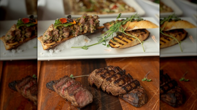 Sliced steak with plated bone marrow in background