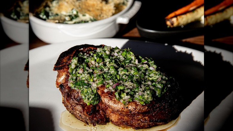 Steak with sauce and seaprate sides blurred in background