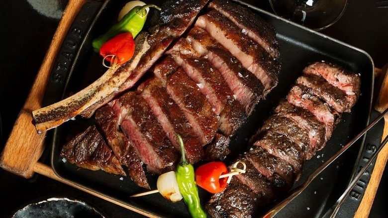 Sliced steak with vegetables on cast iron tray