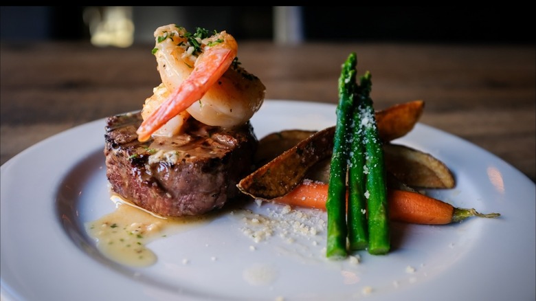 Filet and shrimp on plate with asparagus and veg