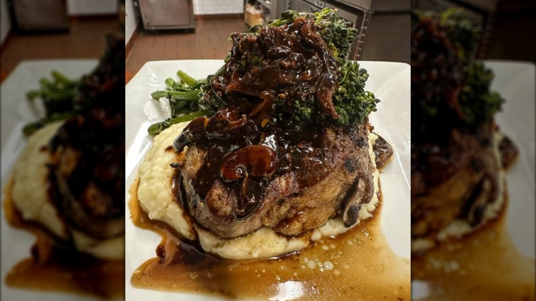 Steak and mushrooms on mashed potatoes on white plate