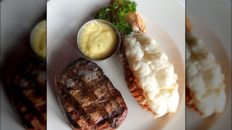 Steak and lobster tail on plate with butter sauce