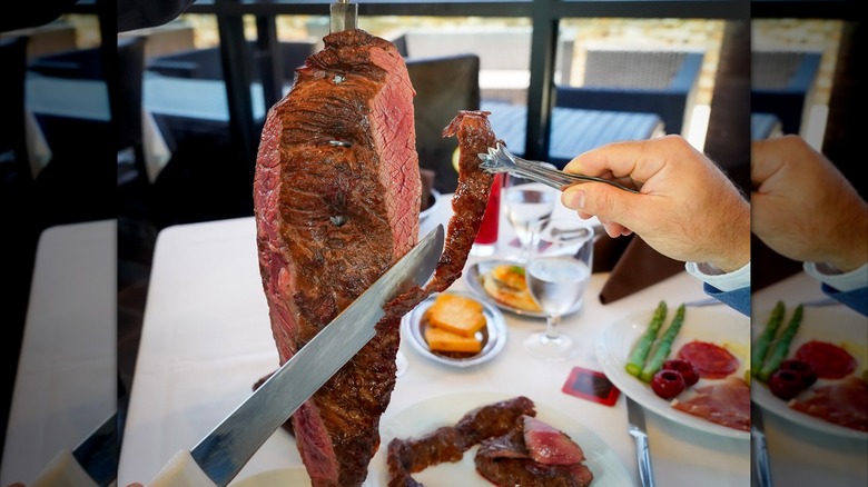 Slicing a piece off a skewer of fraldinha