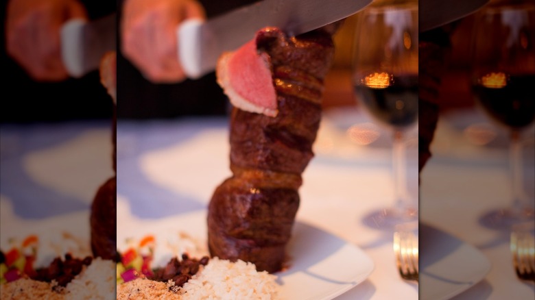 Shaving pieces off sirloin skewer onto plate