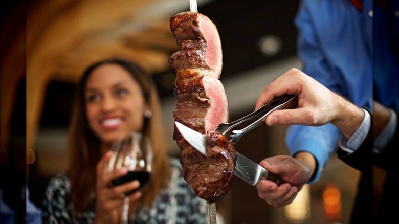 Carving slices of sirloin from skewer against a blurred background