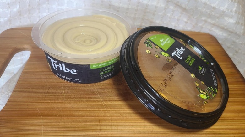 Tribe brand hummus on top of a wooden cutting board in a home kitchen