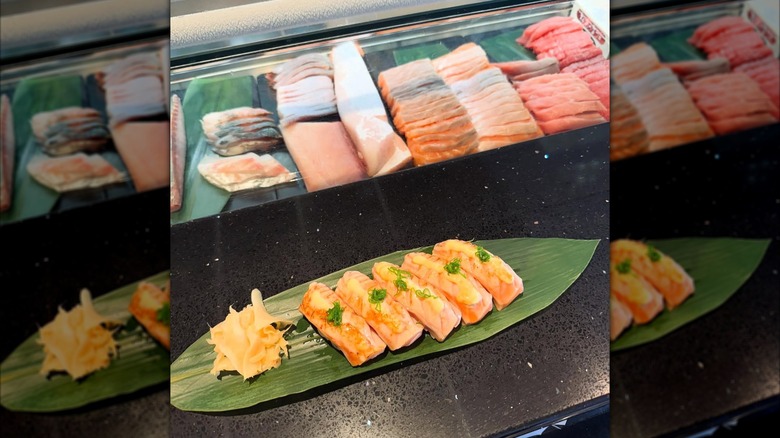 Nigiri topped with spicy mayo on a long waxy leaf plate