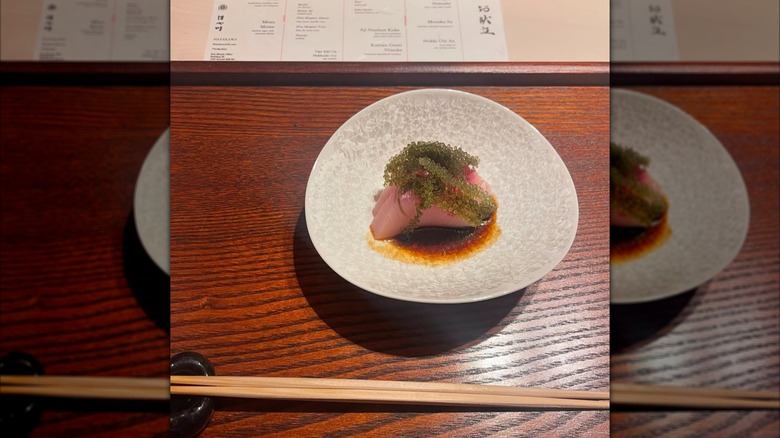 Sashimi topped with soy sauce and sea grapes
