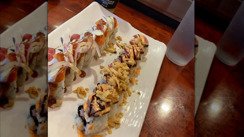 Sushi rolls topped with spicy mayo, tempura flakes and onions
