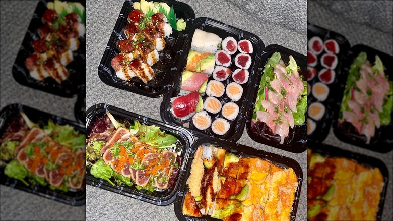 Black to-go containers with assorted sushi, sashimi, uramaki, and salad