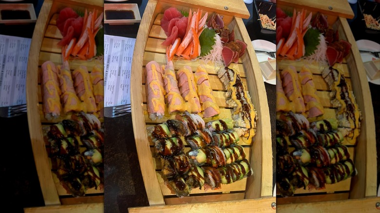 Wooden sushi boat full of assorted rolls and sashimi