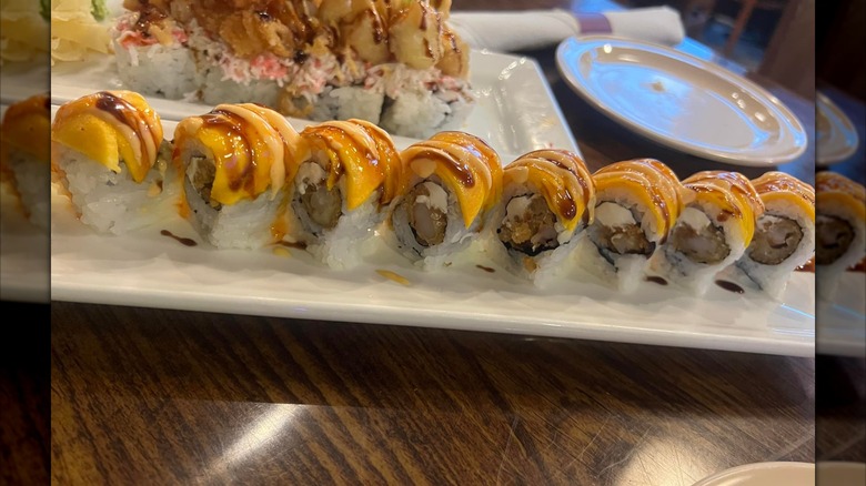 Salmon uramaki roll topped with soy sauce and spicy mayo