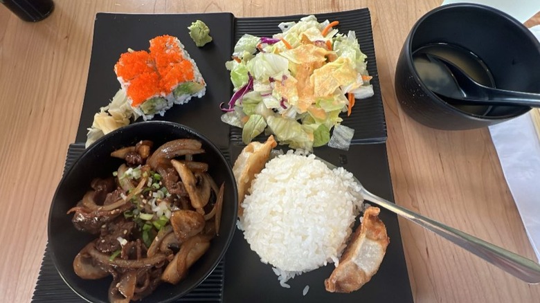 Restaurant combo of rice, sauteed meat and mushrooms, salad, and uramaki rolls