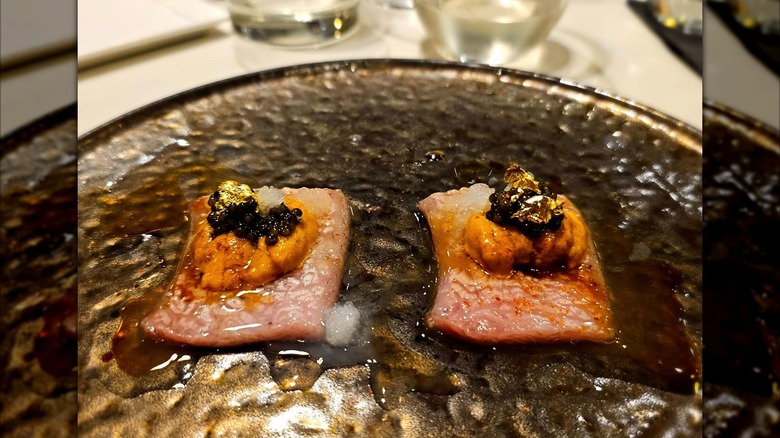 Sashimi on metallic plate topped with caviar and gold flakes