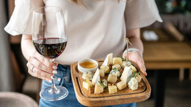 woman carrying cheese board and wine