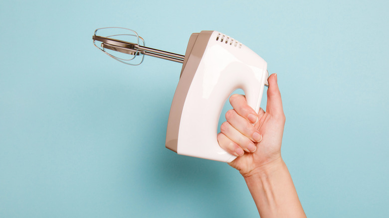 arm holding up electric hand mixer