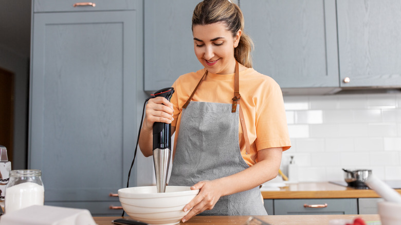 woman using immersion blender in bowl