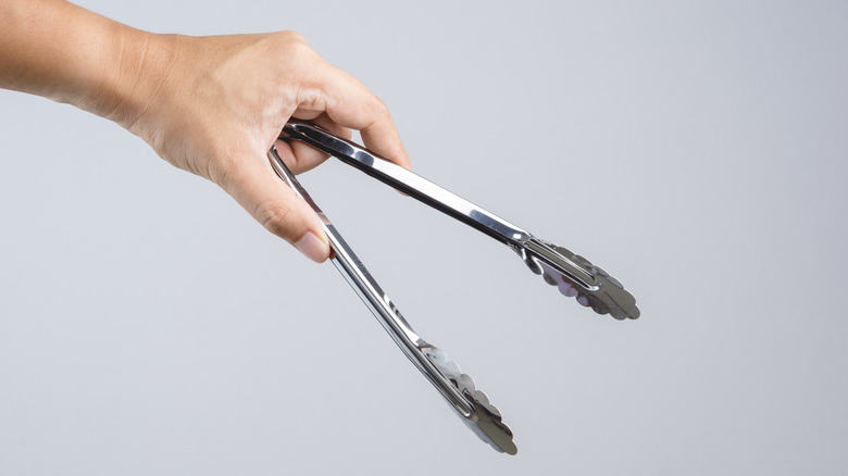 Hand holding kitchen tongs