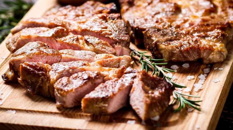 Sliced pork chops with a rosemary sprig on a wooden tray