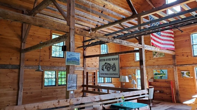 Inside a two-story wooden barn that is home to the tasting room at Oyster River Winery with American flag hanging.