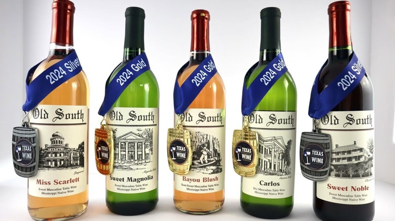 Five Old South Winery bottles with blue ribbons around the necks denoting various accolades.