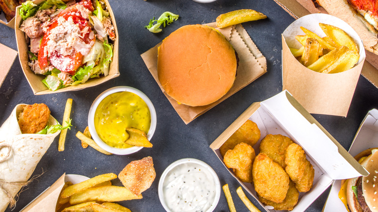 An assortment of fast food items including a salad, burger, chicken nuggets, fries, and dipping sauces