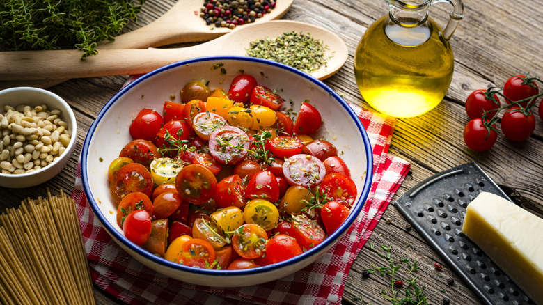 A bowl of cherry tomatoes with thyme, and other seasonings around