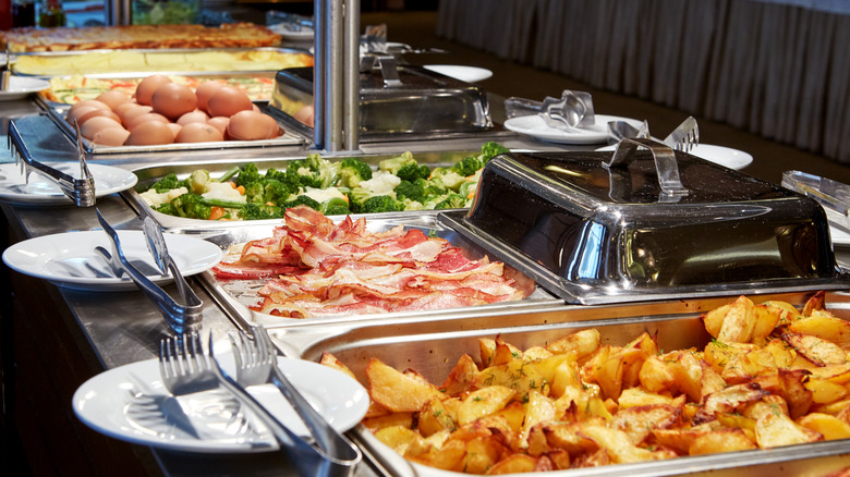 Hotel breakfast buffet with potatoes, eggs, bacon, and vegetables