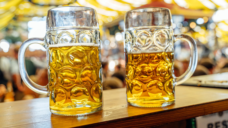 Two partially full stein of beer on a table in an Oktoberfest tent