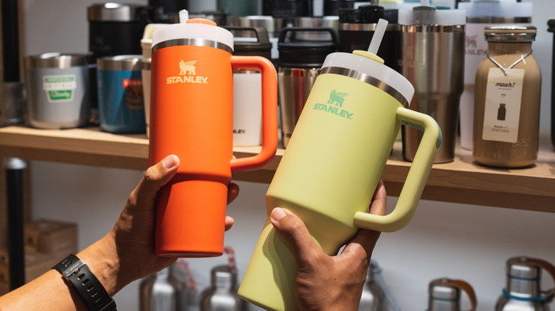 Person holding two Stanley tumblers in a store