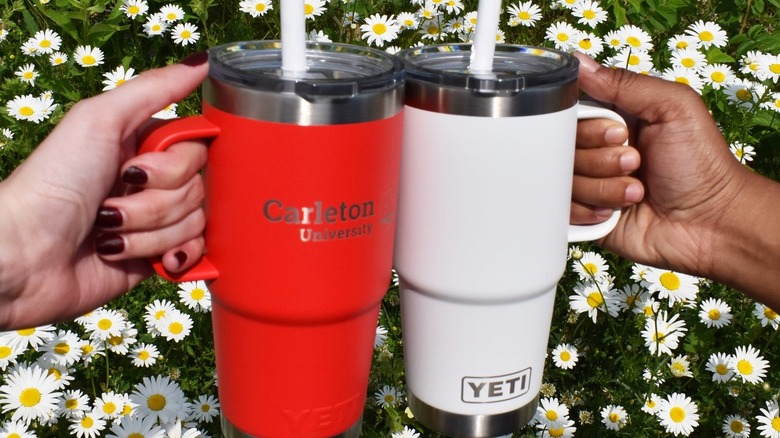Two people holding the handles of Yeti Rambler travel mugs