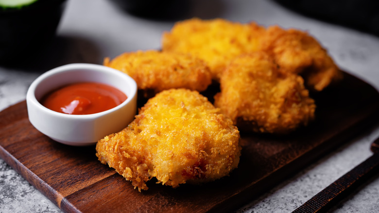 Chicken nuggets on a board with ketchup