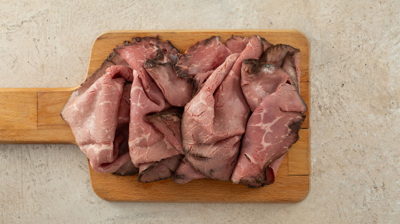 wood board with roast beef deli slices