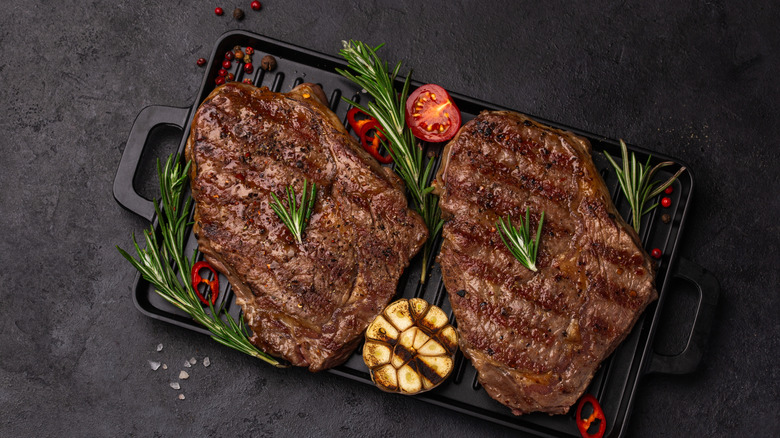 grilled ribeye steaks on a dark serving dish