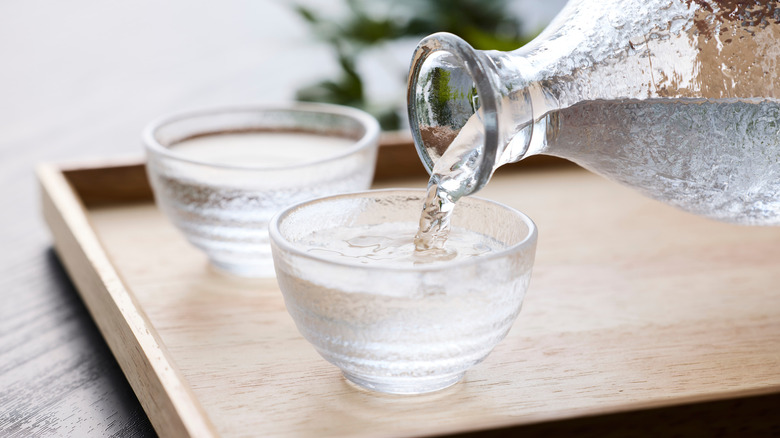 Pouring sake wine from bottle into glasses