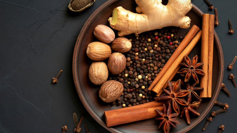 Various whole spices and aromatics in brown dish