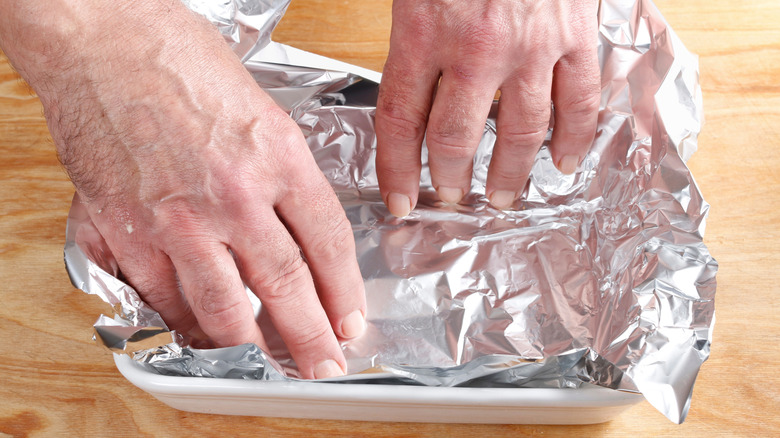 Man lining brownie pan with foil